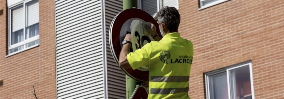 Operario municipal cambiando la señalización del límite de velocidad en la ciudad, de 50 a 30 km/h